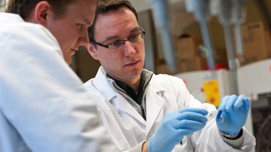 Alexander Stegh, PhD, works in a lab with another researcher